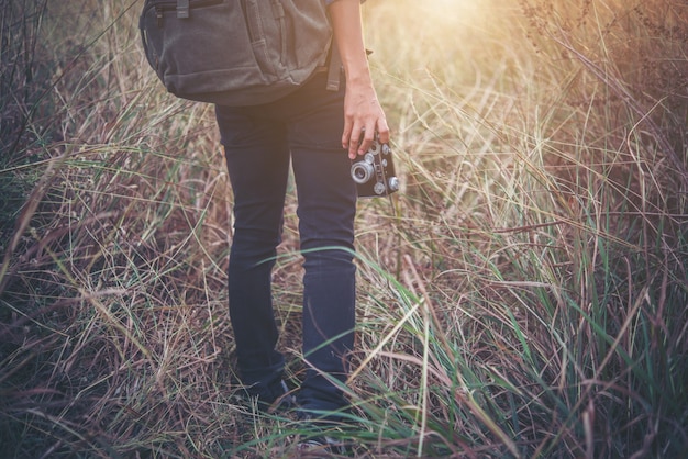 Молодые битник девушка с рюкзаком ходить через в поле летом.