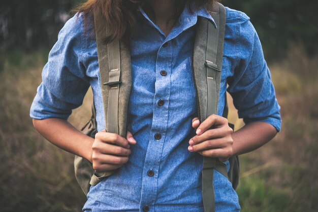 Молодые битник девушка с рюкзаком ходить через в поле летом.