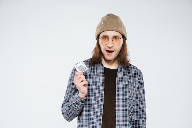 Young hipster holding condom