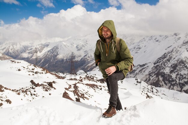 Young hipster man hiking in mountains, winter vacation traveling