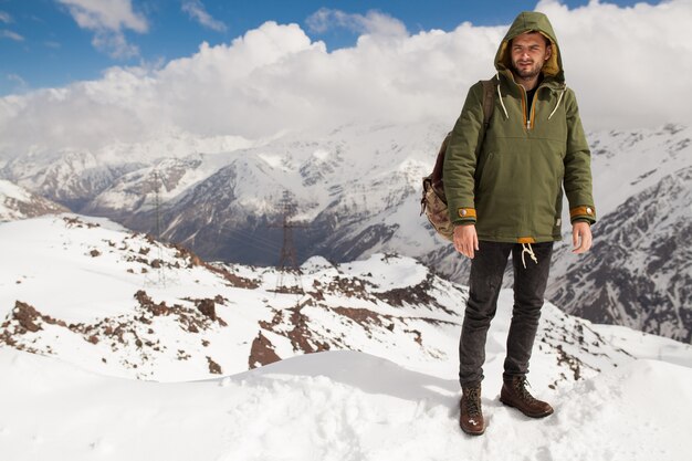 Young hipster man hiking in mountains, winter vacation traveling