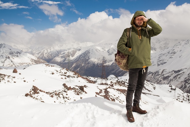 Young hipster man hiking in mountains, winter vacation traveling