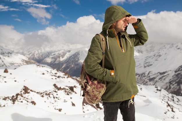 Young hipster man hiking in mountains, winter vacation traveling