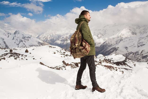 Young hipster man hiking in mountains, winter vacation traveling