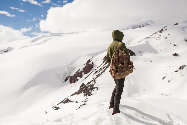 Young hipster man hiking in mountains, winter vacation traveling