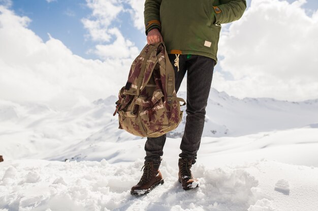 Young hipster man hiking in mountains, winter vacation traveling