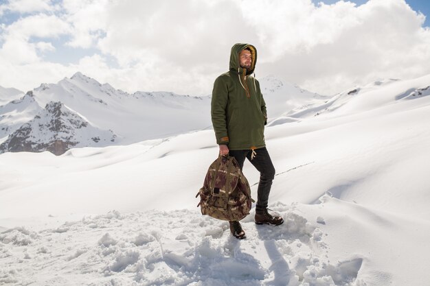 Young hipster man hiking in mountains, winter vacation traveling