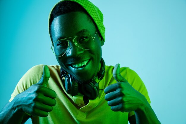 young hipster man listening music with headphones at blue studio with neon lights.