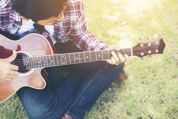 젊은 hipster 남자 공원에서 기타를 연습, 행복과 p를 즐길 수