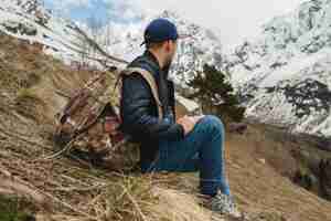 Foto gratuita uomo giovane hipster seduto in montagna