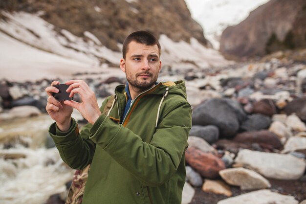 Молодой хипстерский человек, фотографируя с помощью смартфона, дикая природа, зимние каникулы, походы