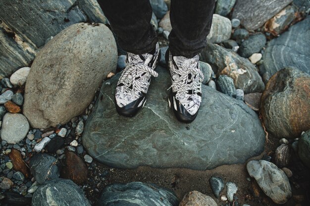 Young hipster man walking on a rock at river in winter forest