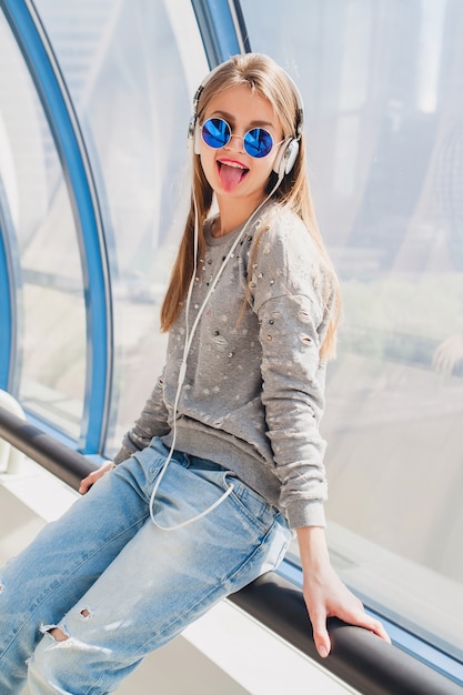 Free photo young hipster woman in casual outfit having fun listening to music in headphones