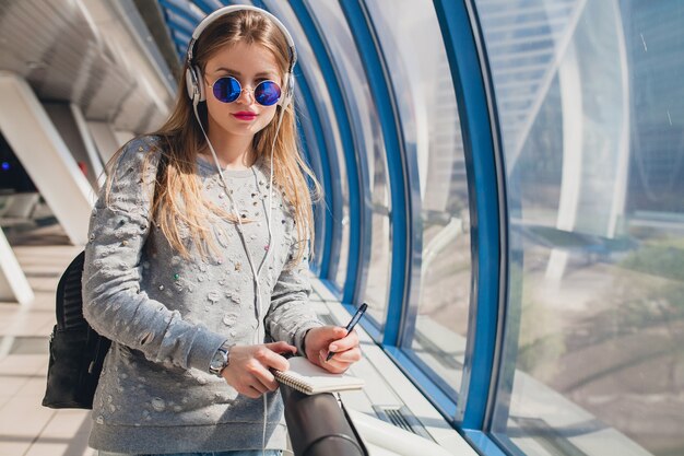 Young hipster woman in casual outfit having fun listening to music in headphones