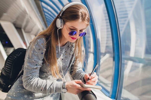 Young hipster woman in casual outfit having fun listening to music in headphones