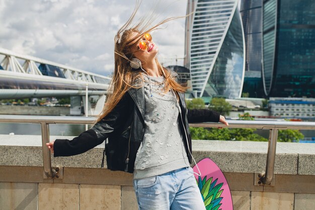 Young hipster woman having fun in street listening to music on headphones