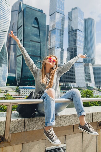 Young hipster woman having fun in street listening to music on headphones