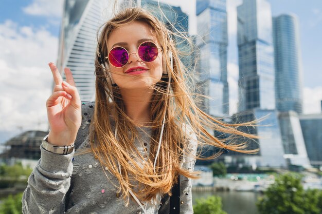 Young hipster woman having fun in street listening to music on headphones