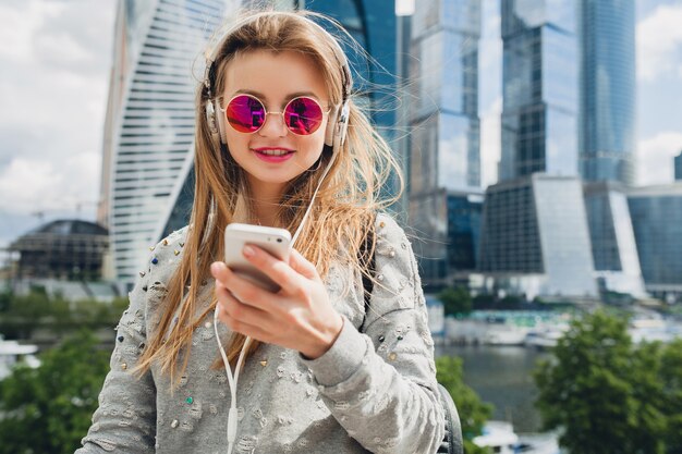 Young hipster woman having fun in street listening to music on headphones