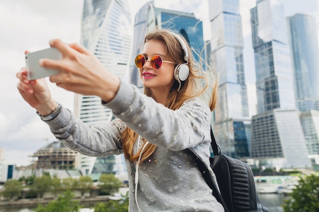 Молодая хипстерская женщина веселится на улице, слушая музыку в наушниках