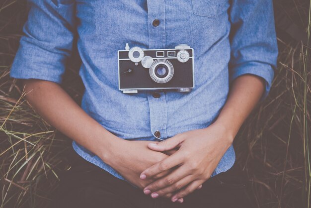 Young hipster woman lying down on summer field after shooting photo.