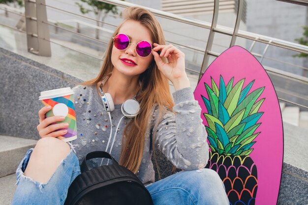 Young hipster woman in street with balance board wearing sweater and jeans