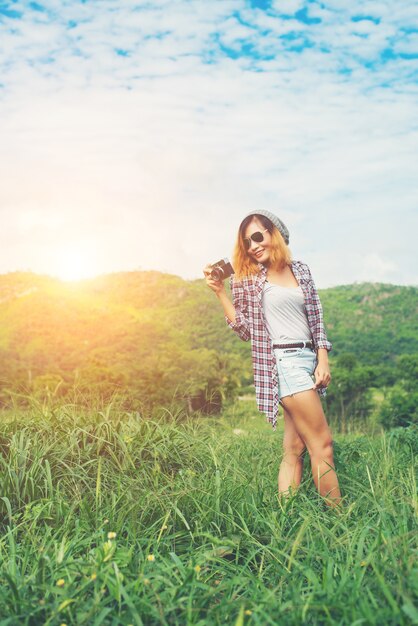 Young Hipster Woman with retro camera taking shot outdoor landsc