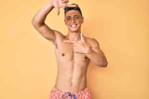 Free photo young hispanic boy wearing swimwear shirtless smiling making frame with hands and fingers with happy face creativity and photography concept