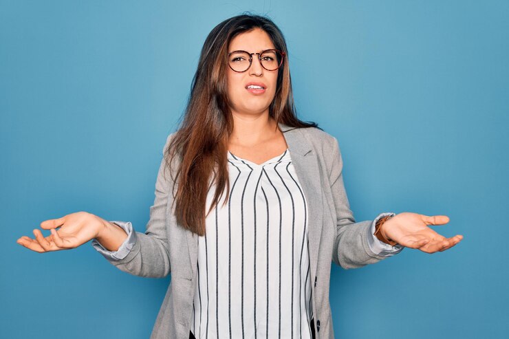 Free Photo young hispanic business woman wearing glasses standing over blue isolated background clueless and confused with open arms no idea concept