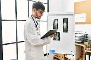 Free photo young hispanic doctor man looking xray working at clinic