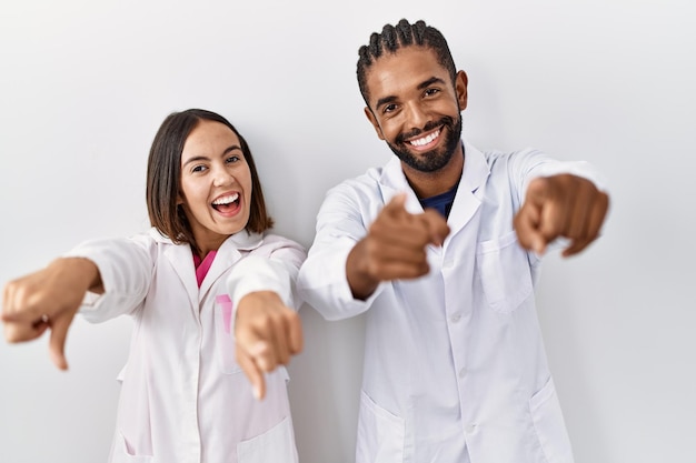 Free photo young hispanic doctors standing over white background pointing to you and the camera with fingers, smiling positive and cheerful