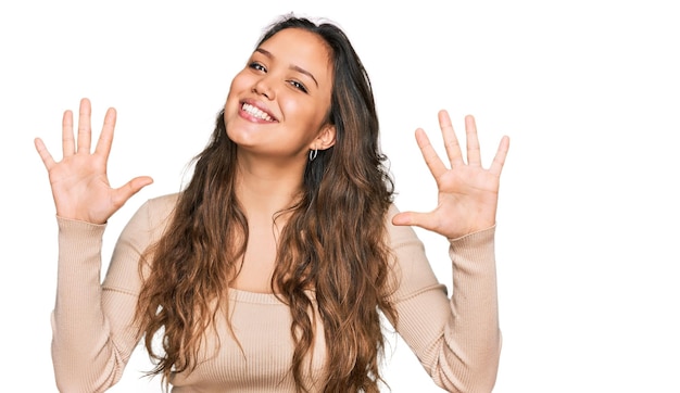 Free photo young hispanic girl wearing casual clothes showing and pointing up with fingers number ten while smiling confident and happy.