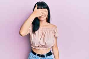 Free photo young hispanic girl wearing casual clothes smiling and laughing with hand on face covering eyes for surprise blind concept