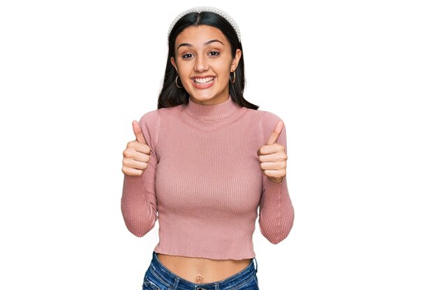 Free photo young hispanic girl wearing casual clothes success sign doing positive gesture with hand thumbs up smiling and happy cheerful expression and winner gesture