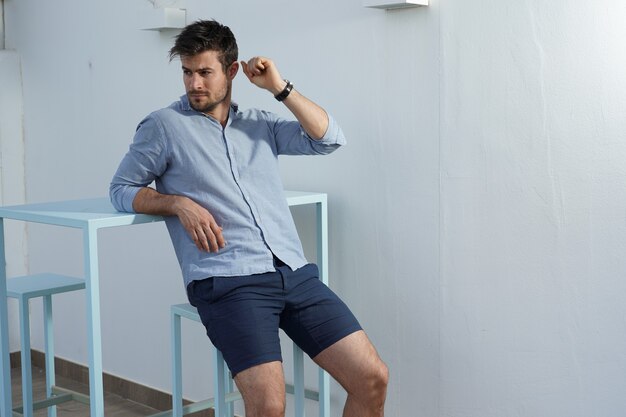 Young Hispanic male wearing a blue shirt posing next to a desk