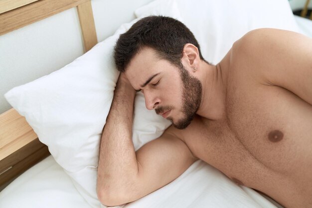 young hispanic man lying on bed sleeping at bedroom