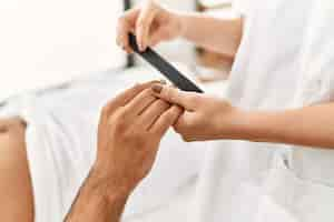 Free photo young hispanic man relaxed having manicure session at beauty center