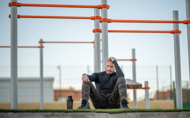 휴식을 취하는 운동장의 잔디에 앉아 있는 젊은 히스패닉 남자
