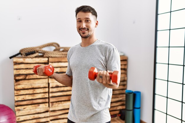 Young hispanic man smiling confident training at sport center