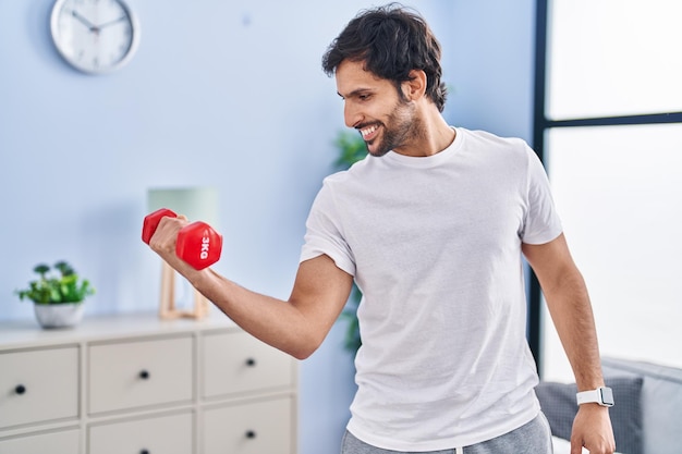 Free photo young hispanic man smiling confident using dumbbell training at home