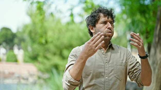 Young hispanic man sweating at park