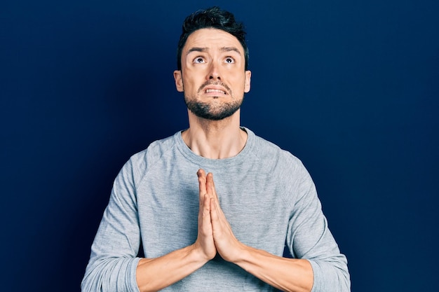 Free photo young hispanic man wearing casual clothes begging and praying with hands together with hope expression on face very emotional and worried begging