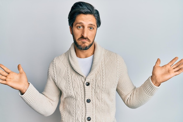 Free photo young hispanic man wearing casual clothes clueless and confused with open arms, no idea and doubtful face.