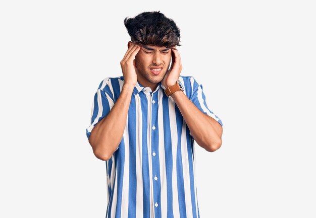 頭に手を当てたカジュアルな服を着た若いヒスパニック系の男性、ストレスのため頭痛。片頭痛に苦しんでいます。