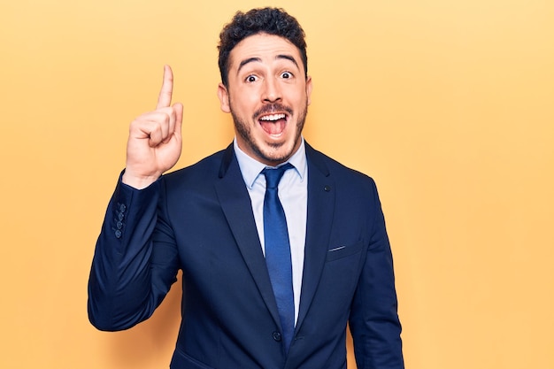 Free photo young hispanic man wearing suit pointing finger up with successful idea exited and happy number one