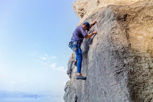 Giovane uomo ispanico con una corda impegnato negli sport di arrampicata su roccia