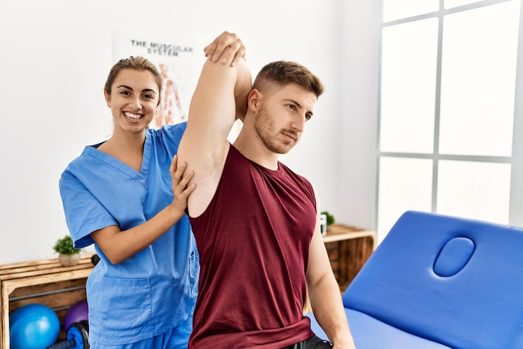 Free Photo young hispanic physioterapist woman make arm rehab treatment to man at the clinic