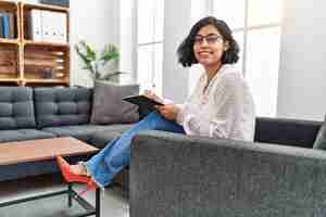 Free photo young hispanic therapist woman working at consultation office looking positive and happy standing and smiling with a confident smile showing teeth