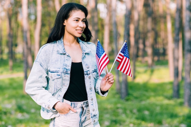 Молодая испанская женщина держит американские флаги