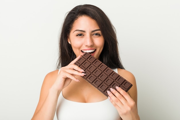 Young hispanic woman holding a chocolate tablet